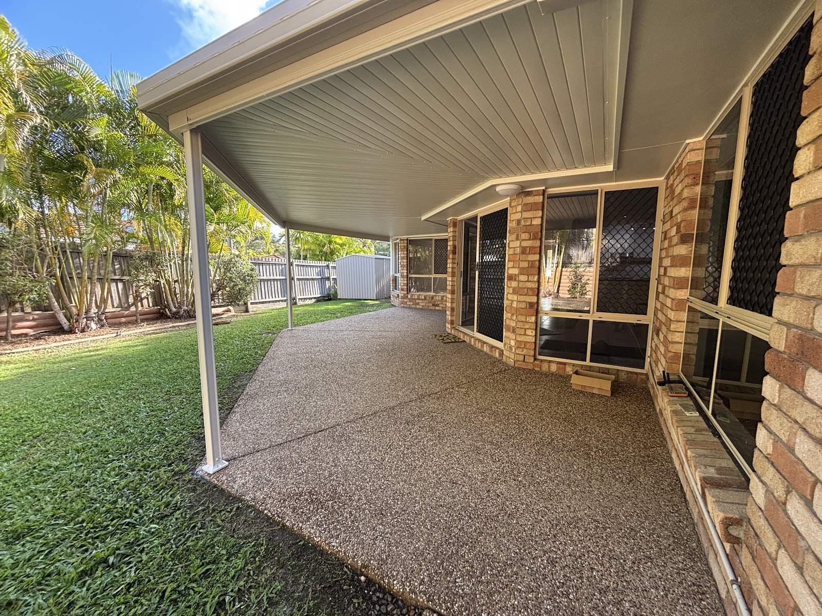 Brick home covered patio with freshly painted white ceiling and posts