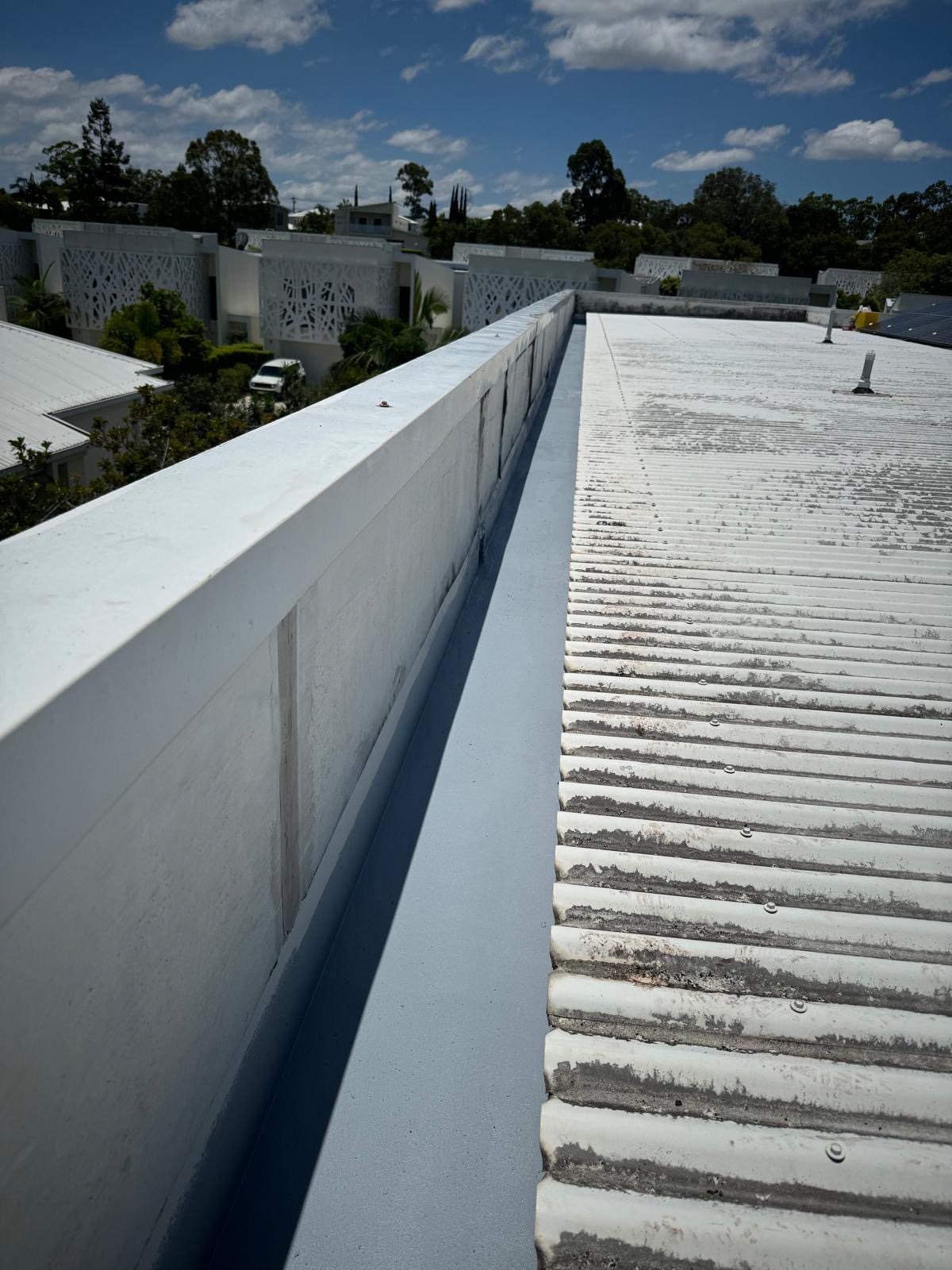 Commercial parapet painted white beside a corrugated roof